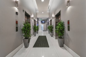 Eine moderne Hotelhalle mit glänzendem Boden, Pflanzen in Töpfen und einem flachbildfernseher an der Wand.