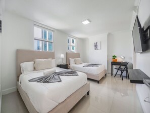 A hotel room with two beds, a desk, a chair, a TV, and a window with a city view. - Private High Rise 3 Bedroom Condo in Brickell (Miami)