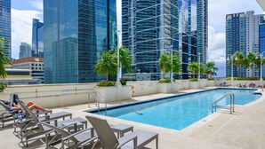 A rooftop pool with lounge chairs and palm trees, surrounded by high-rise buildings. - #3510 · Modern High-Rise Studio in Brickell (Miami)