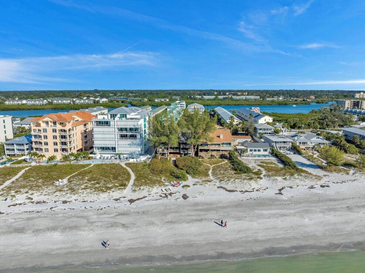 Un hôtel situé sur la côte, composé de plusieurs bâtiments, avec une plage et une vue sur la mer et le paysage environnant.
