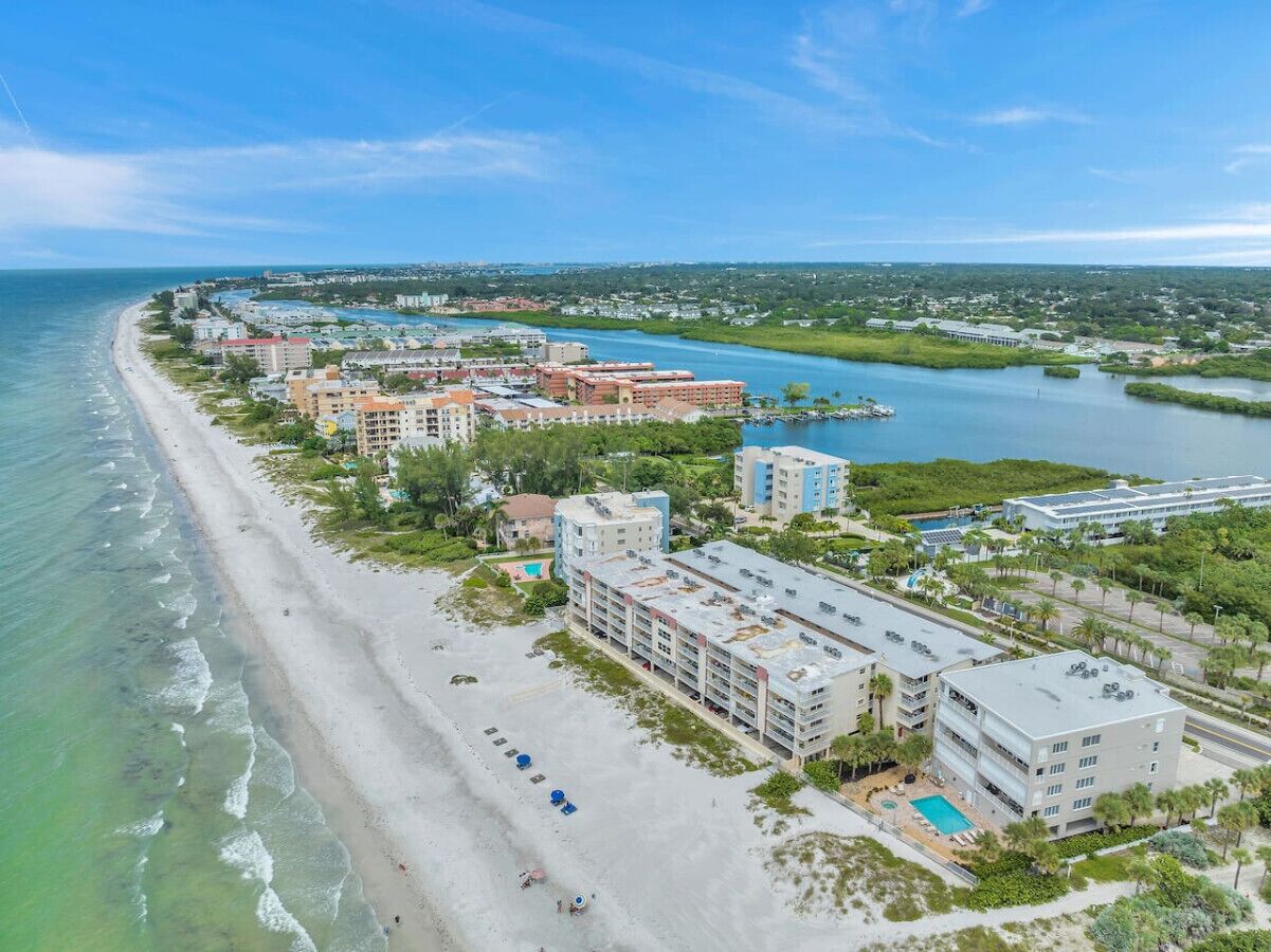 Un hotel costero con varias construcciones, una playa y un puerto deportivo.
