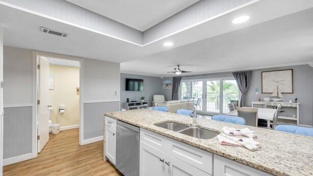 Une cuisine moderne dotée de plans de travail en granit, d’un évier double et d’un coin repas avec des chaises bleues.
