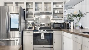 Eine moderne Küche mit Edelstahlgeräten, weißen Schränken und Meerblick.