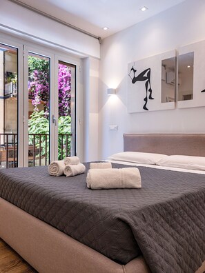 Un dormitorio con cama, almohadas y toallas enrolladas.