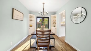 A dining area with a wooden chair, a chandelier, and a mirror on the wall.