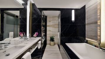 Un baño moderno con un espejo grande, dos lavamanos, una bañera y una planta en maceta.