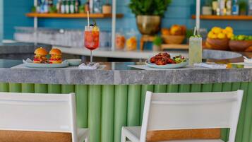 A bar area with a counter, two burgers, a salad, and two drinks.