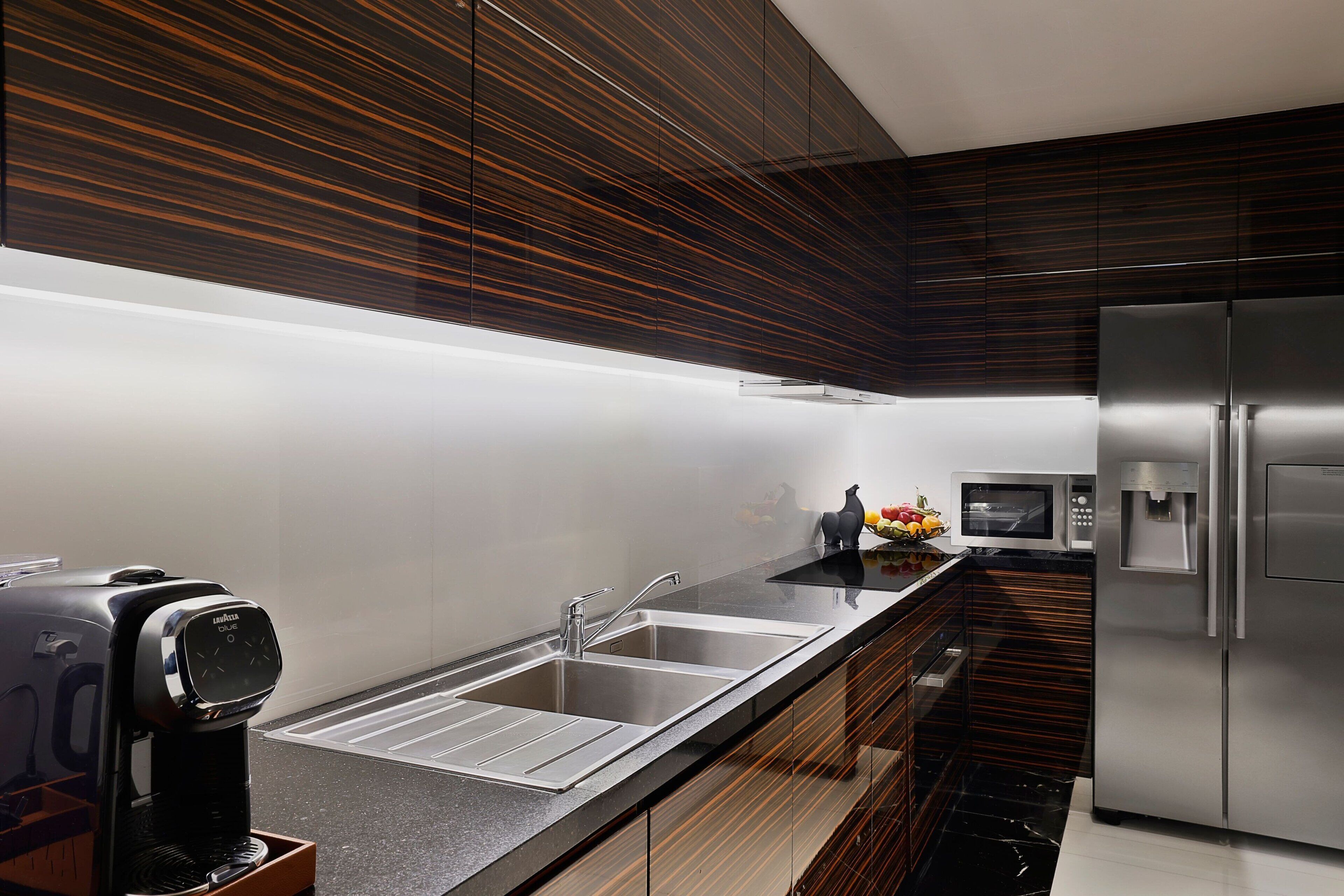 Una cocina moderna con electrodomésticos de acero inoxidable, cafetera integrada y microondas.