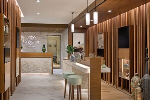 A modern spa reception area with a marble floor, wooden paneling, and a reception desk.