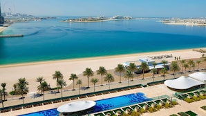 A resort with a pool, beach, and palm trees.