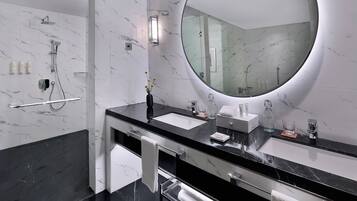 Une salle de bain moderne avec deux lavabos, un grand miroir et une douche.