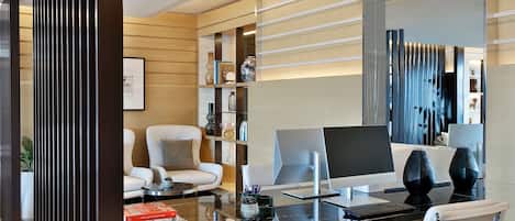 A modern office space with a glass desk, a white leather chair, and a bookshelf.
