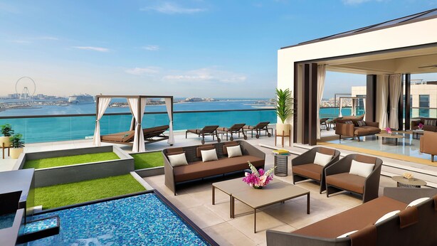 A rooftop terrace with a pool, seating area, and a view of the sea and cityscape.