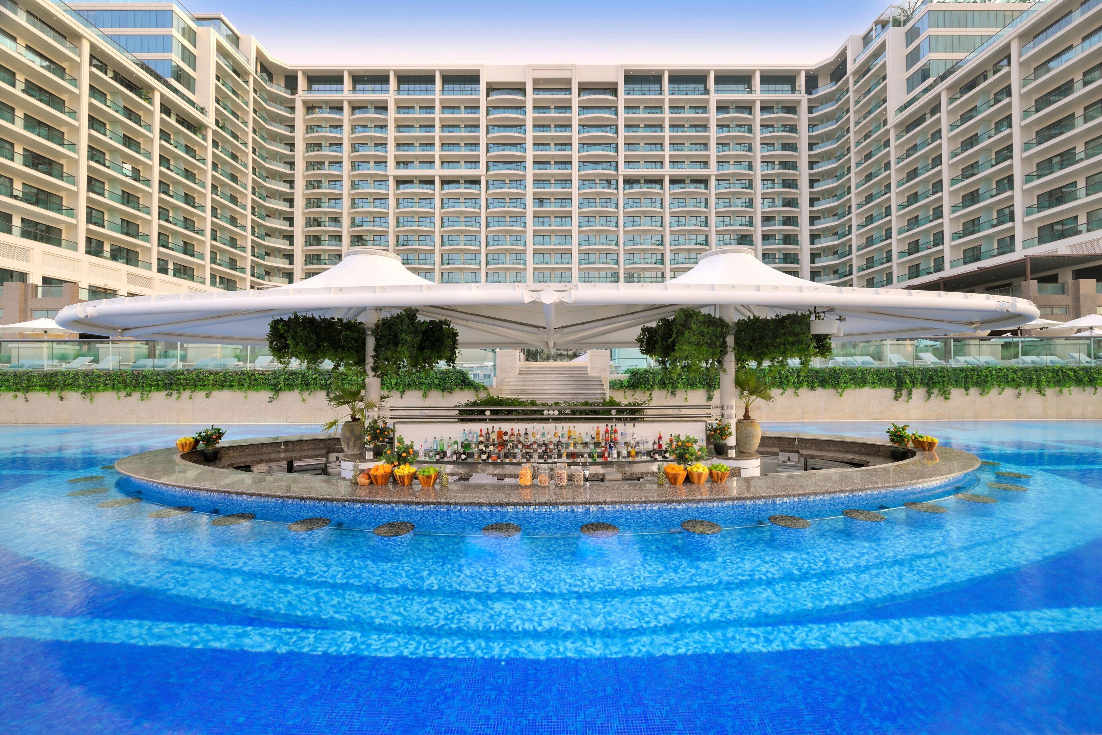 A large hotel with a central pool area, surrounded by multiple floors of residential units.