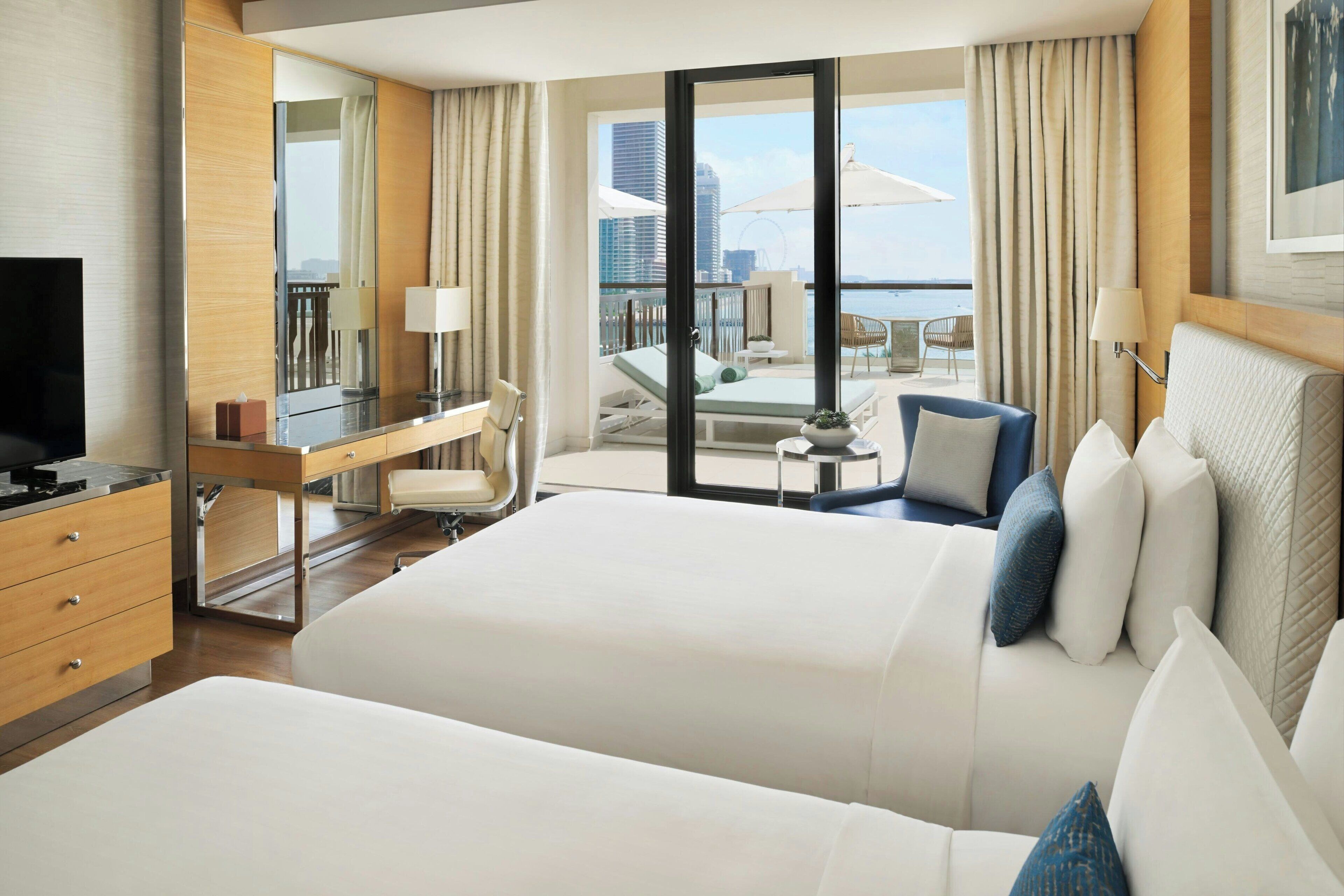 Ein Hotelzimmer mit Balkon, Schreibtisch, Bett und Fernseher.
