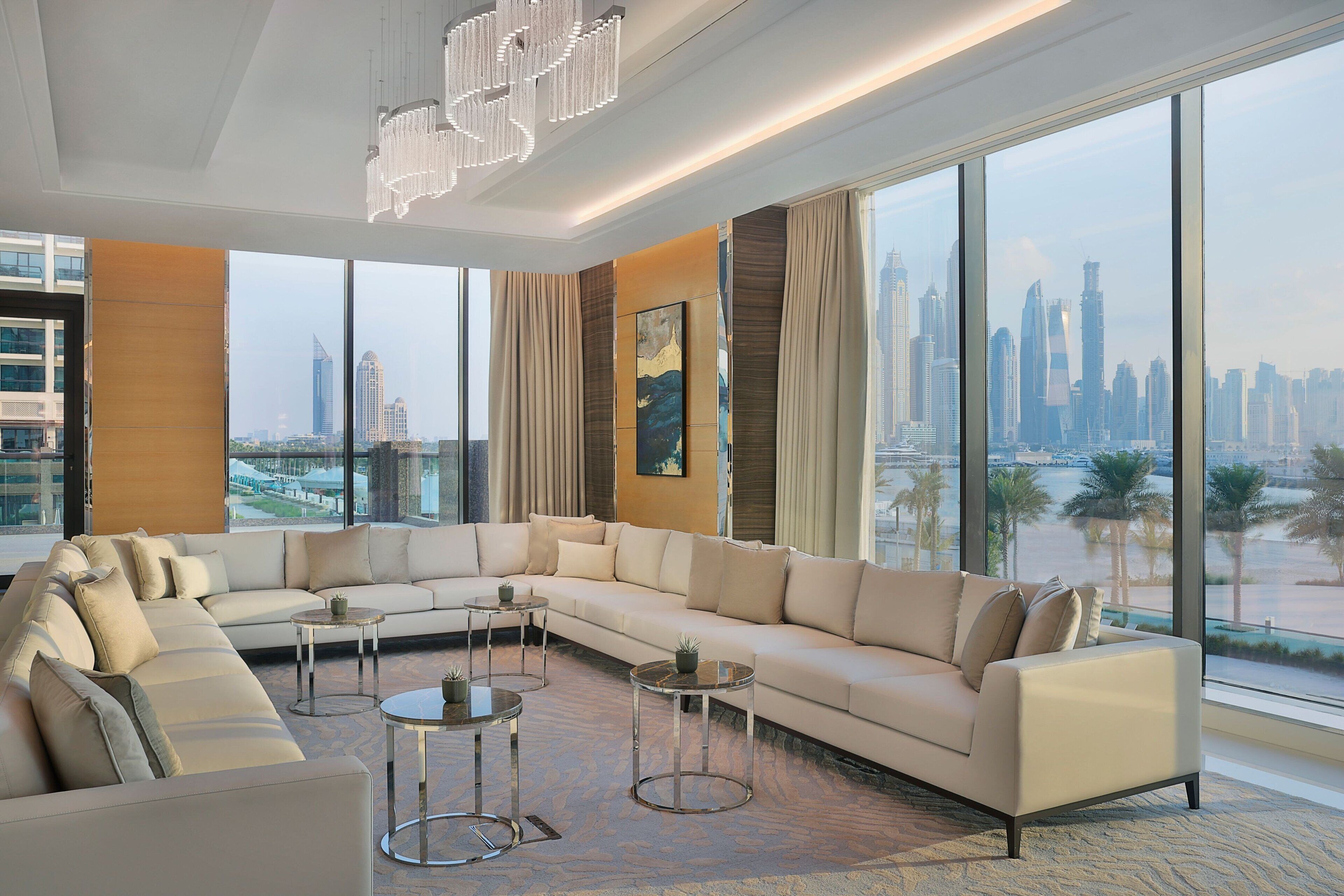 A modern living room with a large sectional sofa, two small side tables, and a large window offering a city view.