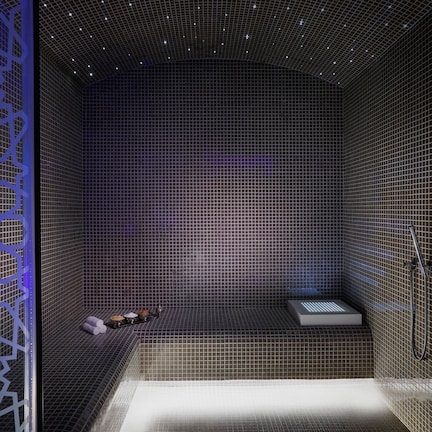 A modern bathroom with a tiled floor, a built-in bench, and a shower area.