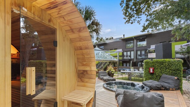 A wooden sauna with a bench, a hot tub, and outdoor seating.