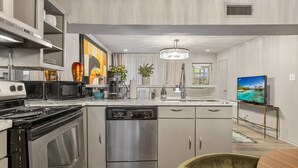 A modern kitchen with stainless steel appliances, a dishwasher, and a dining area with a wooden table and chairs.
