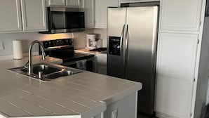 A modern kitchen with white cabinetry, stainless steel appliances, and a central island.