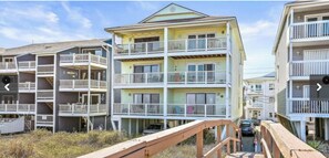 Stunning coastal residence with balconies and access to the beach via a wooden walkway.