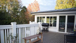 A covered patio with a wooden deck, a white fence, a bench, a grill, and a table with chairs. - Awesome home in Kalmar with WiFi (Virserum)