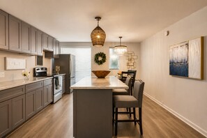 A modern kitchen with a central island, stainless steel appliances, and pendant lighting. - An inviting two-bedroom condo with a bright open layout, tranquil garden views, and a private patio overlooking a beautifully landscaped courtyard and pool.🎡 STAY MINUTES FROM THE STATE FAIR OF TEXAS! 🎡 (Dallas)