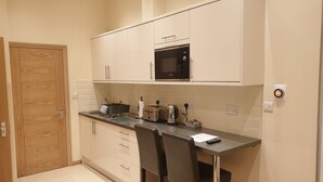 A compact kitchen with white cabinets, a Bosch microwave, a toaster, and a kettle on the countertop. - London Luxury 1 bed studio 5 mins from Ilford Stn free parking (London)