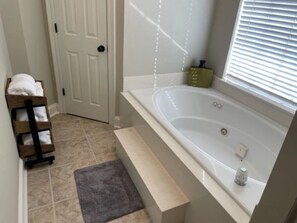 A bathroom with a bathtub, a towel rack, and a window with blinds. - Enchanting lake home with amazing views! Very Safe (Baton Rouge)