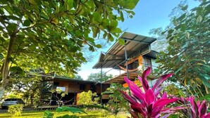 Een modern huis met een zonnepaneel dak, omringd door weelderige begroeiing en een tuin.