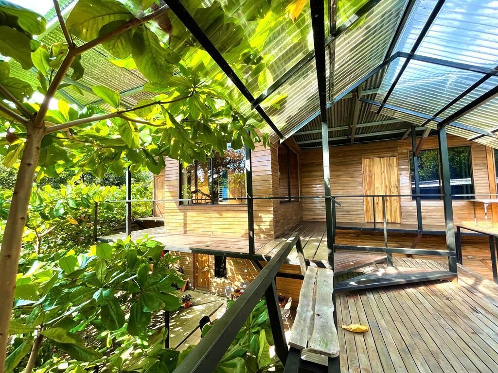 A covered outdoor area with wooden decking, metal railings, and a transparent roof structure.