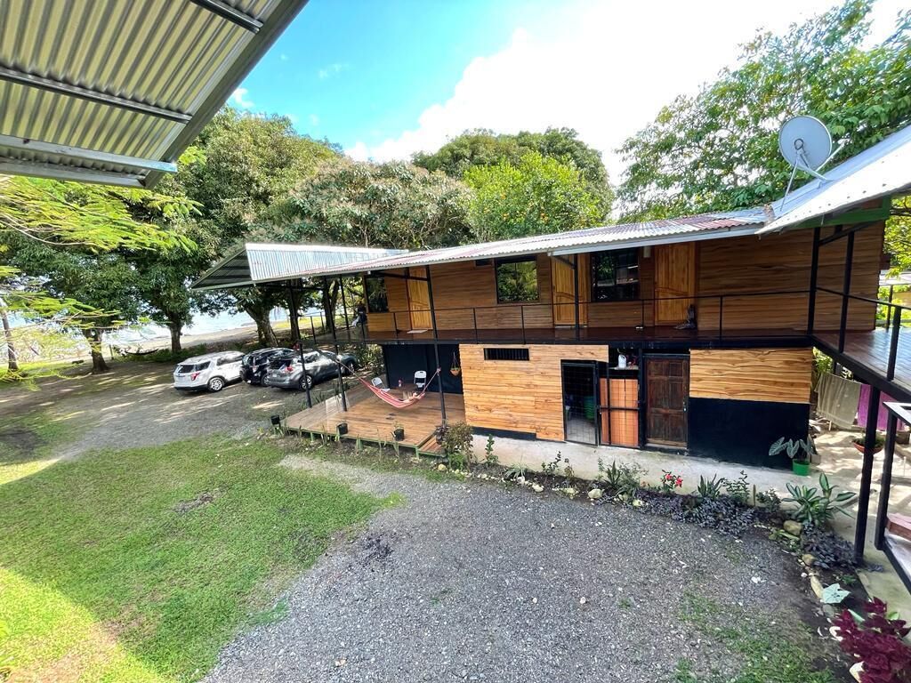 Un bâtiment moderne à deux étages, doté d’un toit plat, d’une antenne parabolique et d’un espace extérieur couvert avec un hamac.