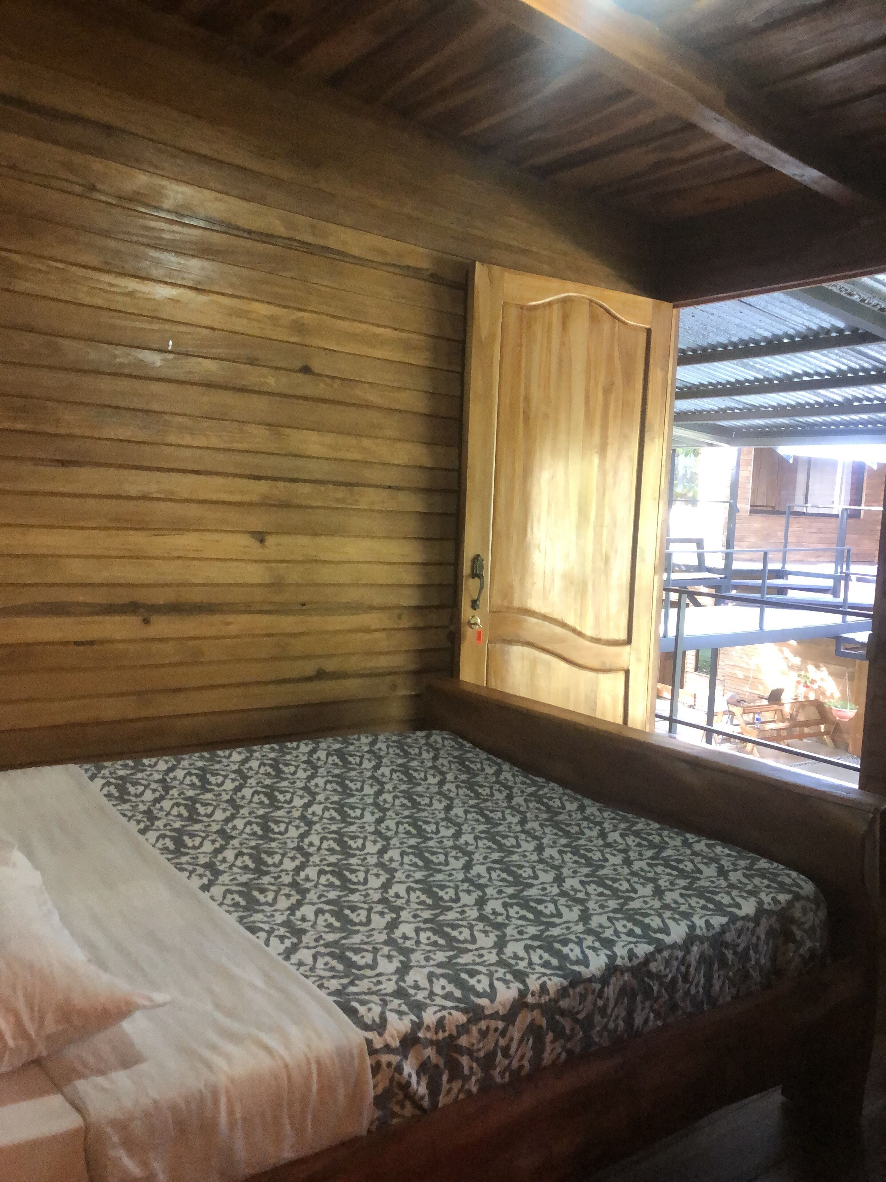 A wooden room with a bed, a window, and a door.