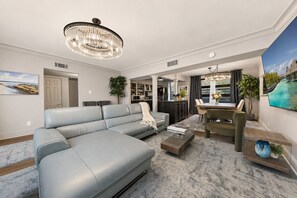 A modern living room with a sectional sofa, a dining area, and a kitchen in the background.