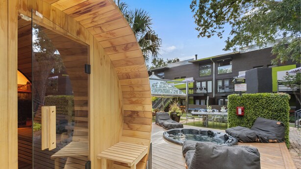 Een houten sauna met een bank, een whirlpool en buiten zitplaatsen.