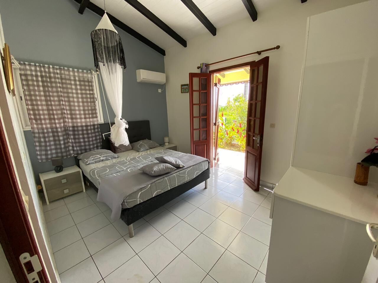 A bedroom with a bed, bedside table, and a window with curtains.