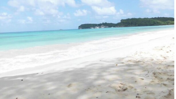 Una playa con arena blanca y agua turquesa cristalina.