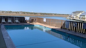 Una piscina con muelle de madera, un puesto de socorrista y vista al agua.