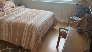 Un dormitorio con cama, una silla, una mesa, una lámpara y una ventana con vistas a un pantano.
