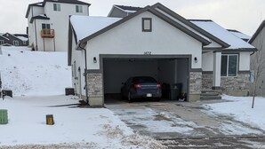 A residential garage with a car parked inside, a stone facade, and a number 1672 on the garage door.