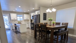 A spacious kitchen with white cabinets, a central island, and a dining area with wooden chairs and a table.