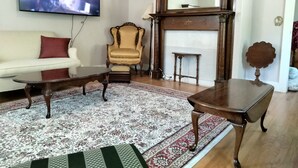 En stue med sofa, sofabord, lænestol, tv, pejs og et stort spejl.