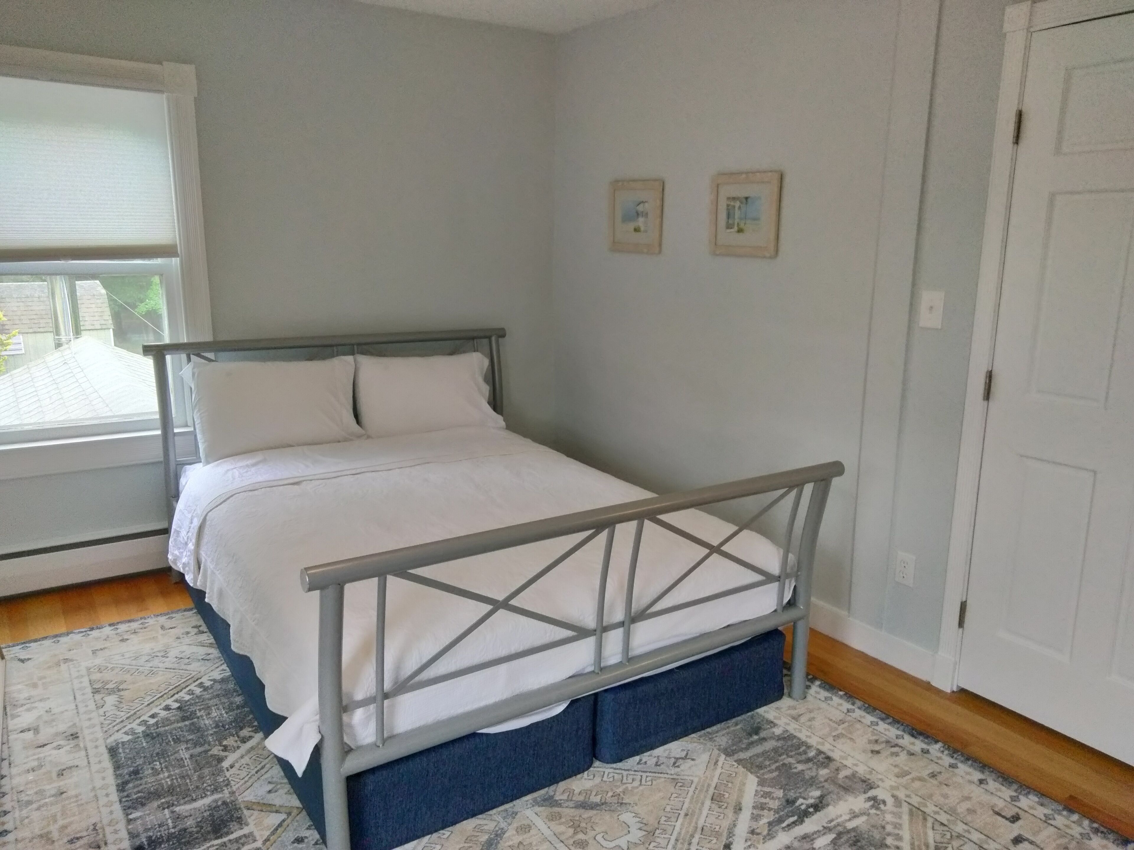 A bedroom with a bed, a window, and a door.