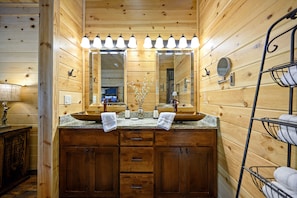 Un bagno in una cabina di legno con doppio lavabo, uno specchio grande e un porta asciugamani.