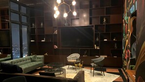 Un salon moderne doté d’un grand téléviseur à écran plat, de sièges confortables et offrant une vue sur la ville.