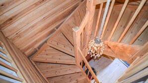 A spiral staircase made of wooden planks with a chandelier hanging from the center.