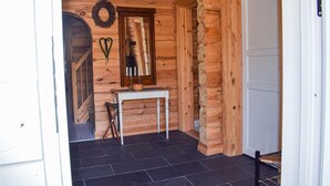 A wooden interior with a white door, a small table with a mirror, and a wreath on the wall.