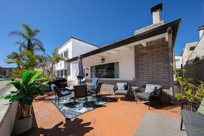 Un patio con mobiliario exterior, una parrilla y un muro de ladrillo.