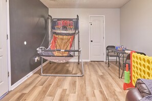 A room with a basketball hoop, a dining table, and exercise equipment.