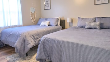 Ein Schlafzimmer mit zwei Betten, einem Nachttisch, einer Lampe und Wandbildern.